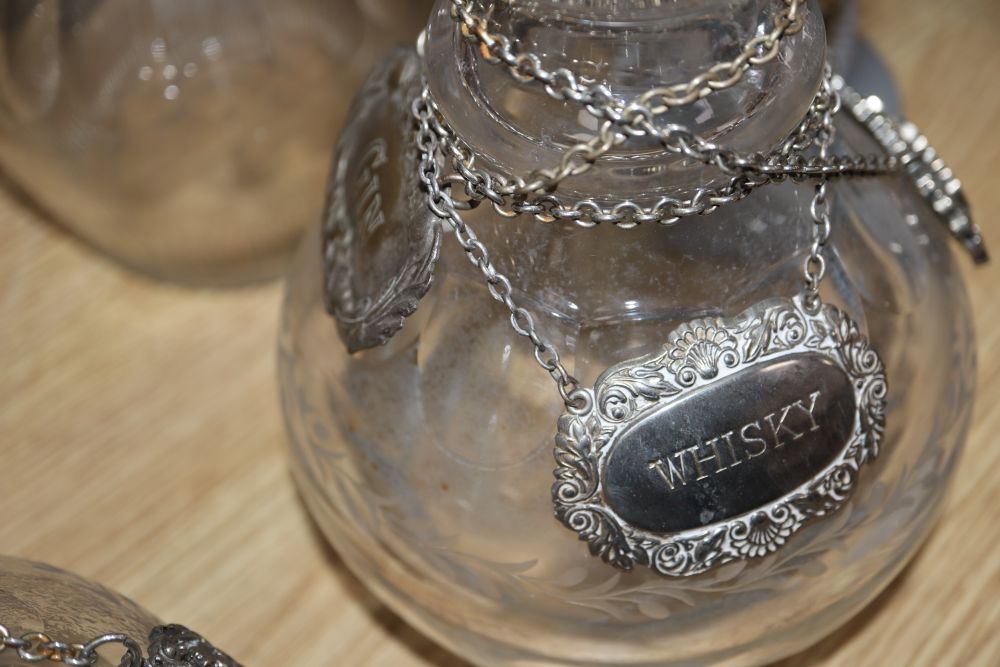 A pair of cut glass decanters, three other decanters, a claret jug and other glassware together with various labels, one silver whisky